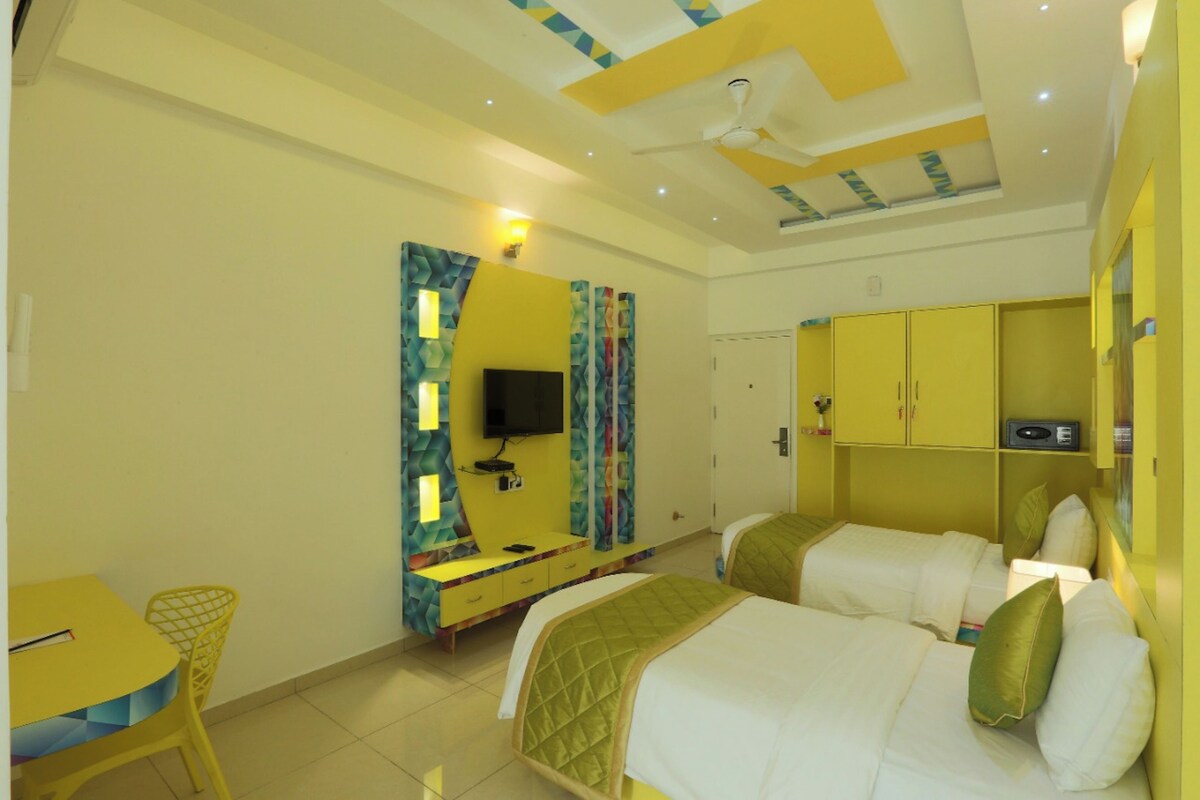 Ein Hotelzimmer mit zwei Betten, einem Fernseher, einem Schreibtisch und gelben Schränken.