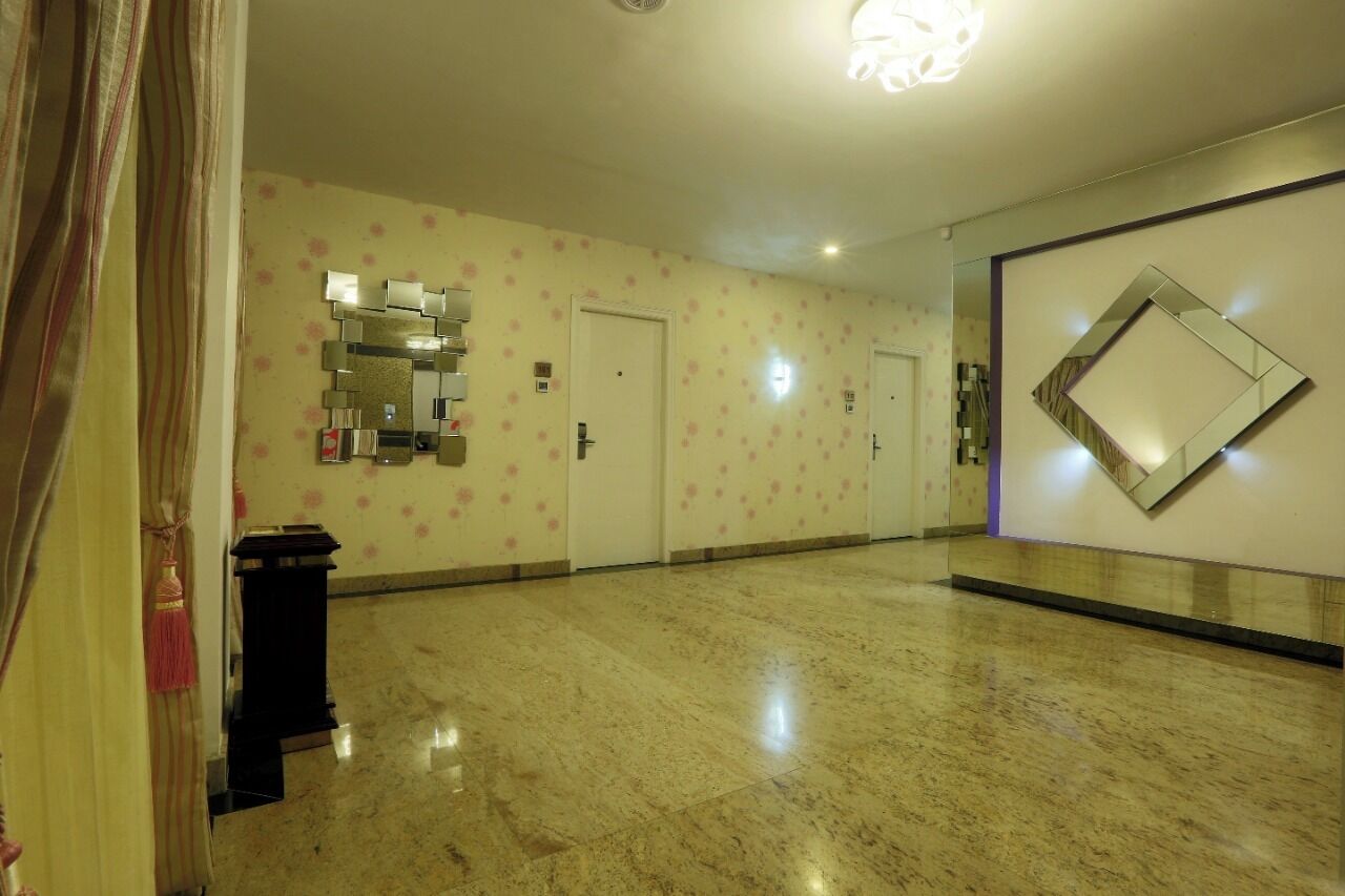 A hallway with a marble floor, a wall-mounted mirror, and a door with a floral pattern.