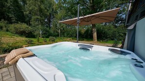A hot tub with a beige towel, surrounded by greenery and a patio umbrella. - Country Mill between Moselle and Hunsrück (Bernkastel-Kues)