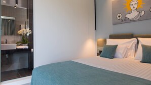 Une chambre moderne avec un grand lit, une table de chevet, une commode, un miroir et une œuvre d’art accrochée au mur.