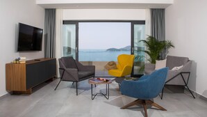 Un salon moderne avec une grande télévision, un canapé, un fauteuil bleu et un fauteuil jaune, ainsi qu’une petite table basse.