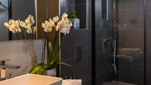 Une salle de bain moderne avec un grand miroir, un lavabo blanc et un espace douche.