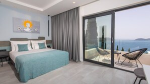 Une chambre moderne avec un grand lit, un balcon donnant sur la mer et un tableau représentant le soleil accroché au mur.