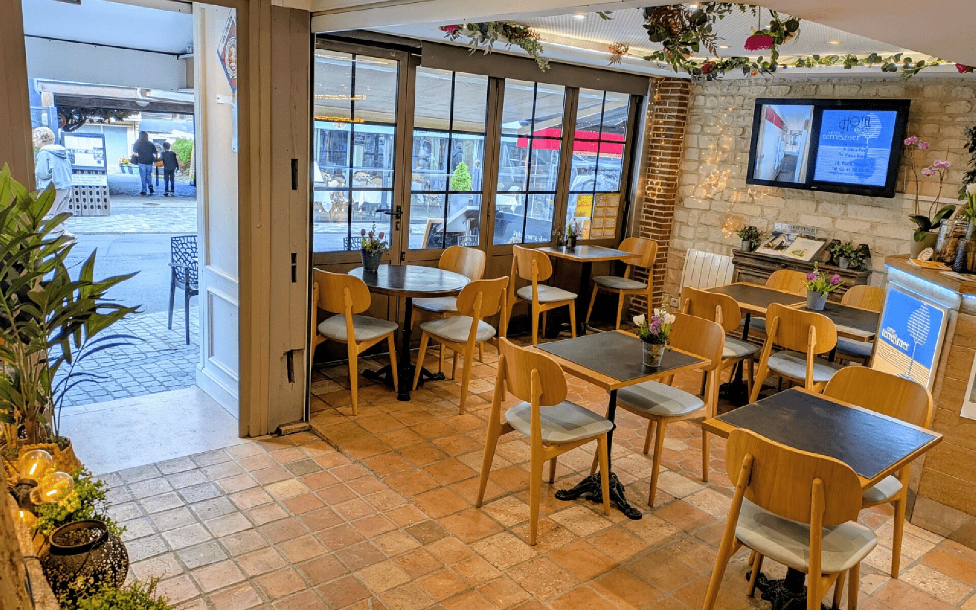 Un restaurant avec des chaises et des tables en bois, un mur en pierre et un écran de télévision diffusant du contenu.