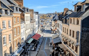 Uma rua estreita, ladeada por edifícios altos, alguns com lojas no térreo.