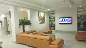 Un amplio salón con un sofá de cuero grande, un televisor montado en la pared y una escalera que sube a un nivel superior.