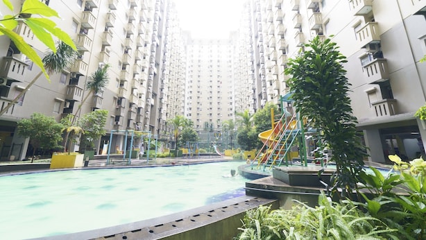 Edifici residencial amb piscina, àrea de jocs i vegetació.