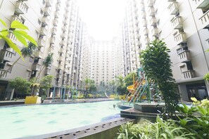 Un immeuble résidentiel doté d’une piscine, d’aires de jeux pour enfants et d’espaces verts.