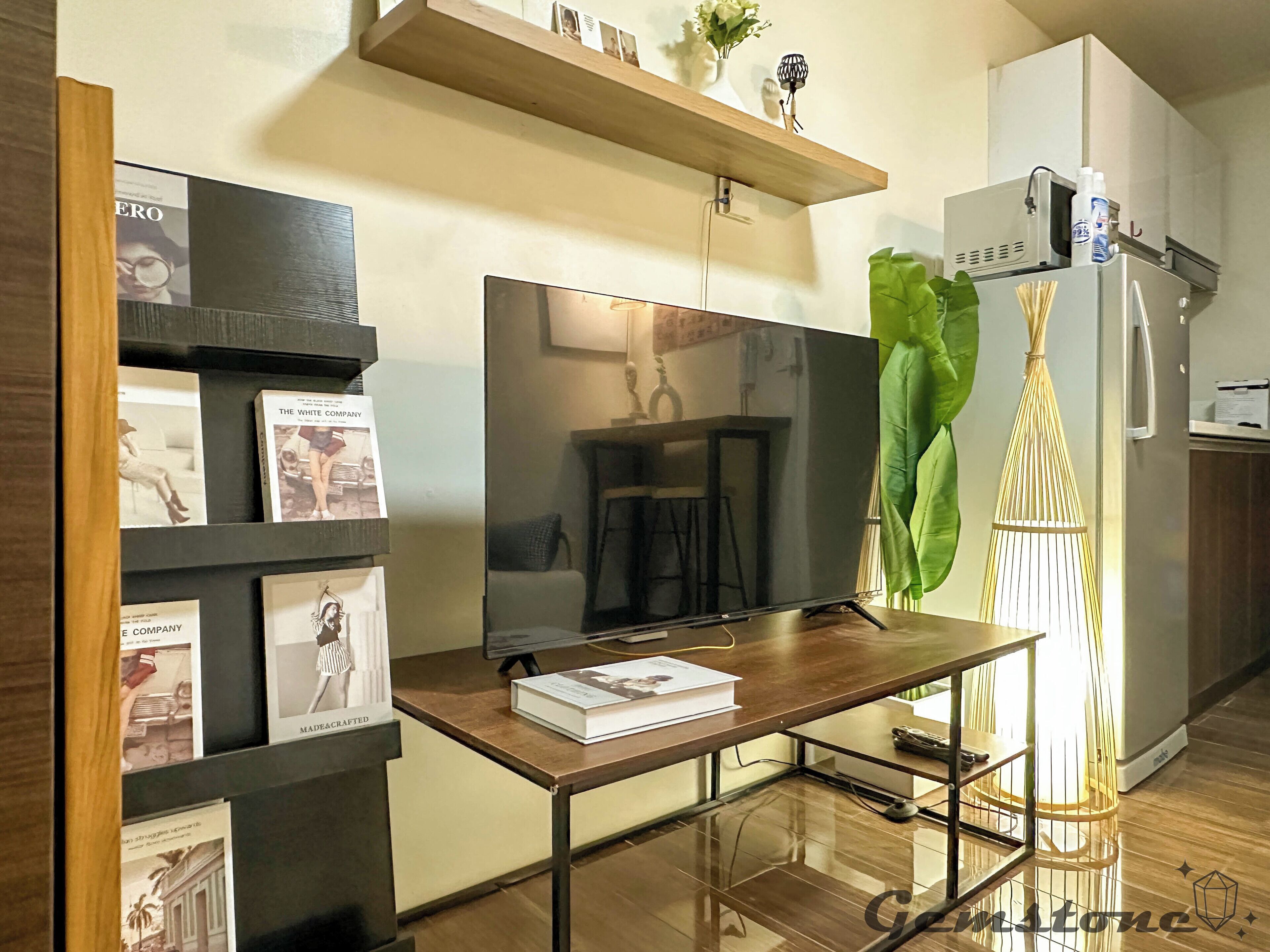 A modern kitchen with a wooden countertop, a built-in TV, and a refrigerator.