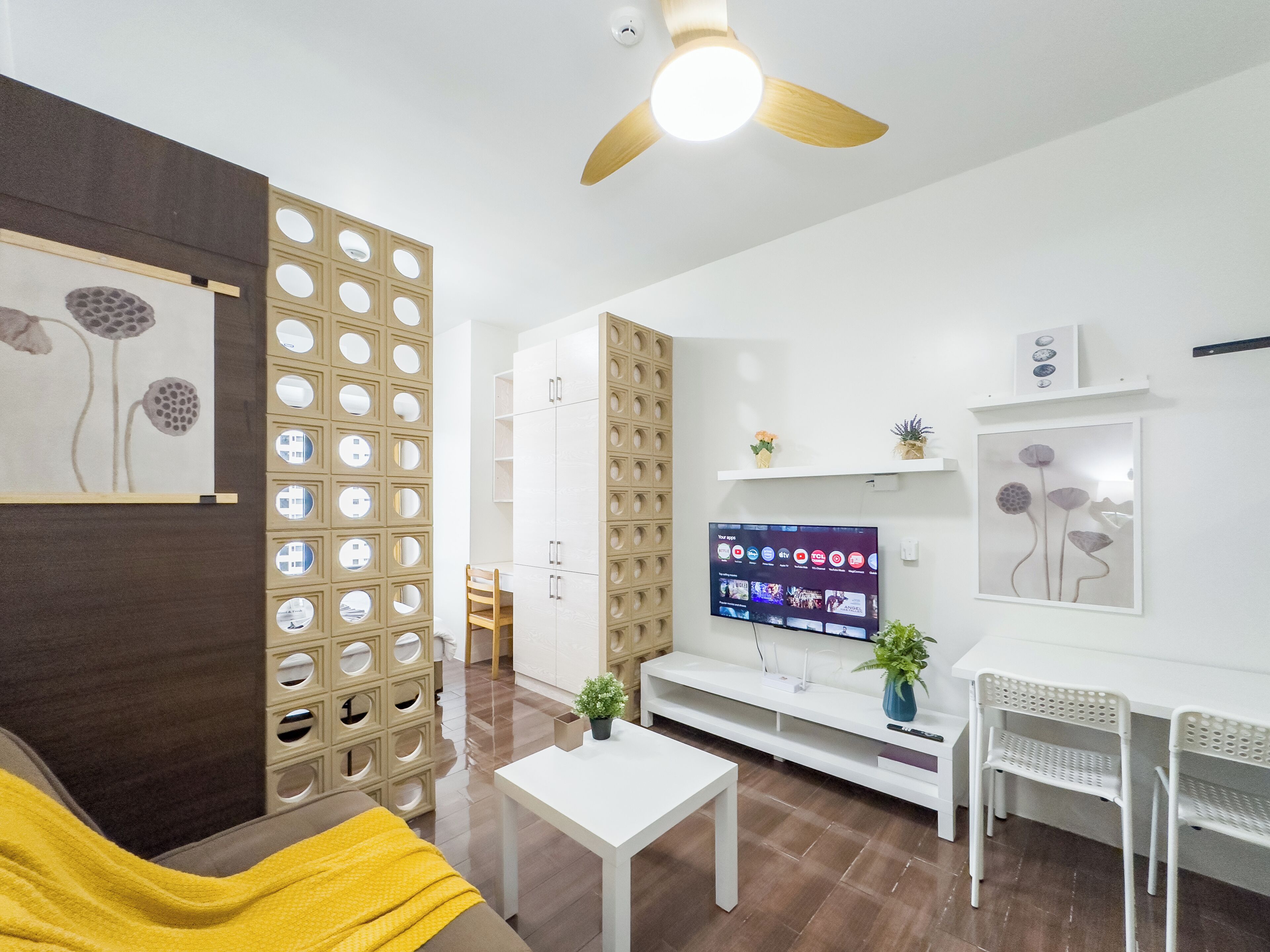 A modern living room with a flat-screen TV, white furniture, and a decorative wall panel.