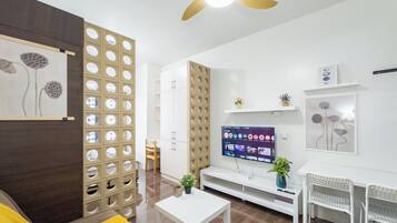 Una sala de estar moderna con un televisor de pantalla plana, muebles blancos y un panel decorativo en la pared.