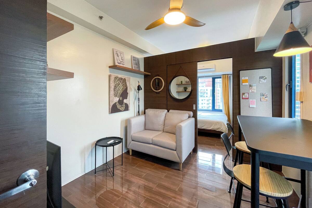 Una sala de estar moderna con un sofá, una mesa de comedor y un ventilador de techo.