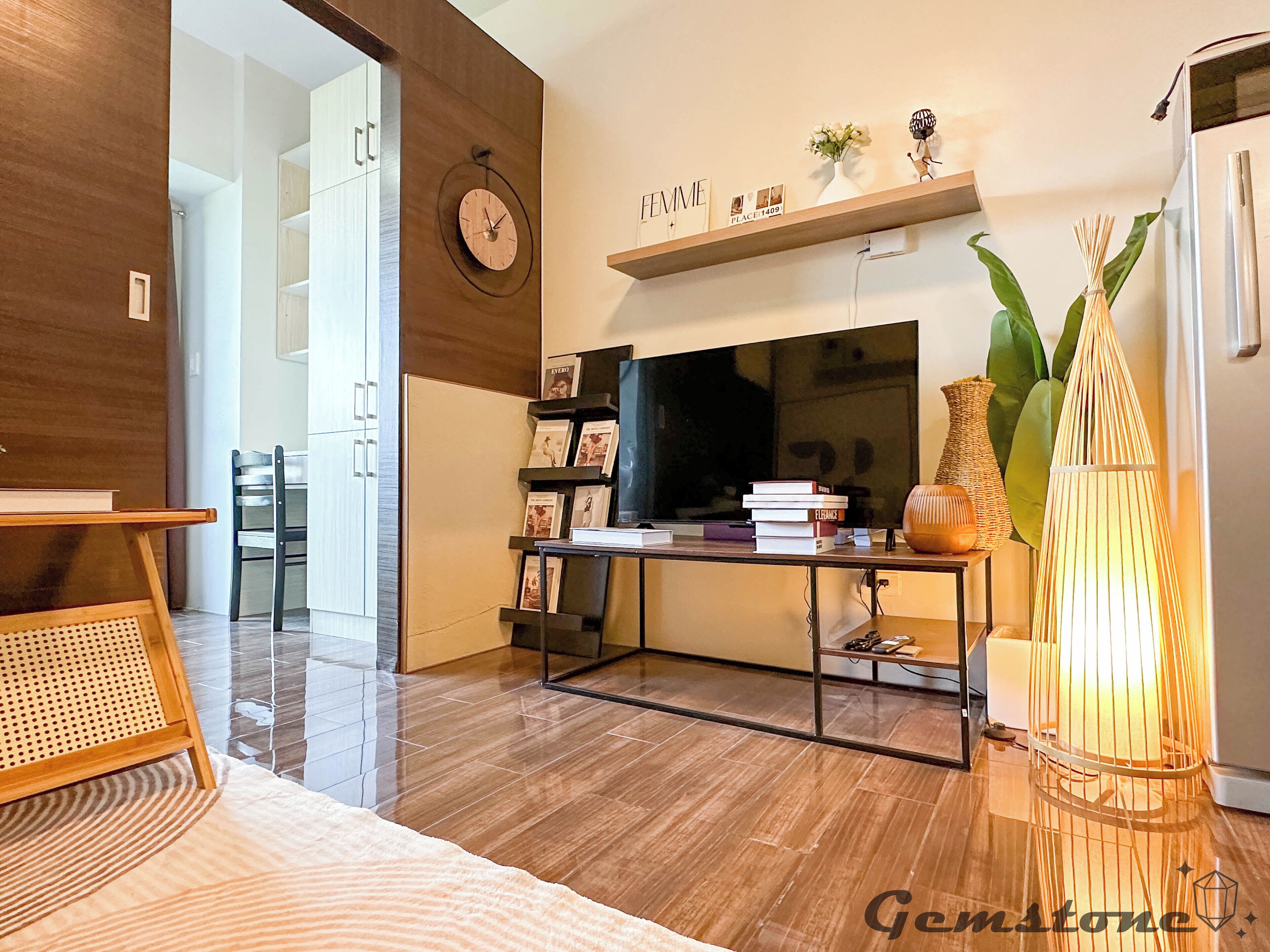 Een moderne woonkamer met een houten vloer, een televisie, een boekenkast en een decoratieve lamp.