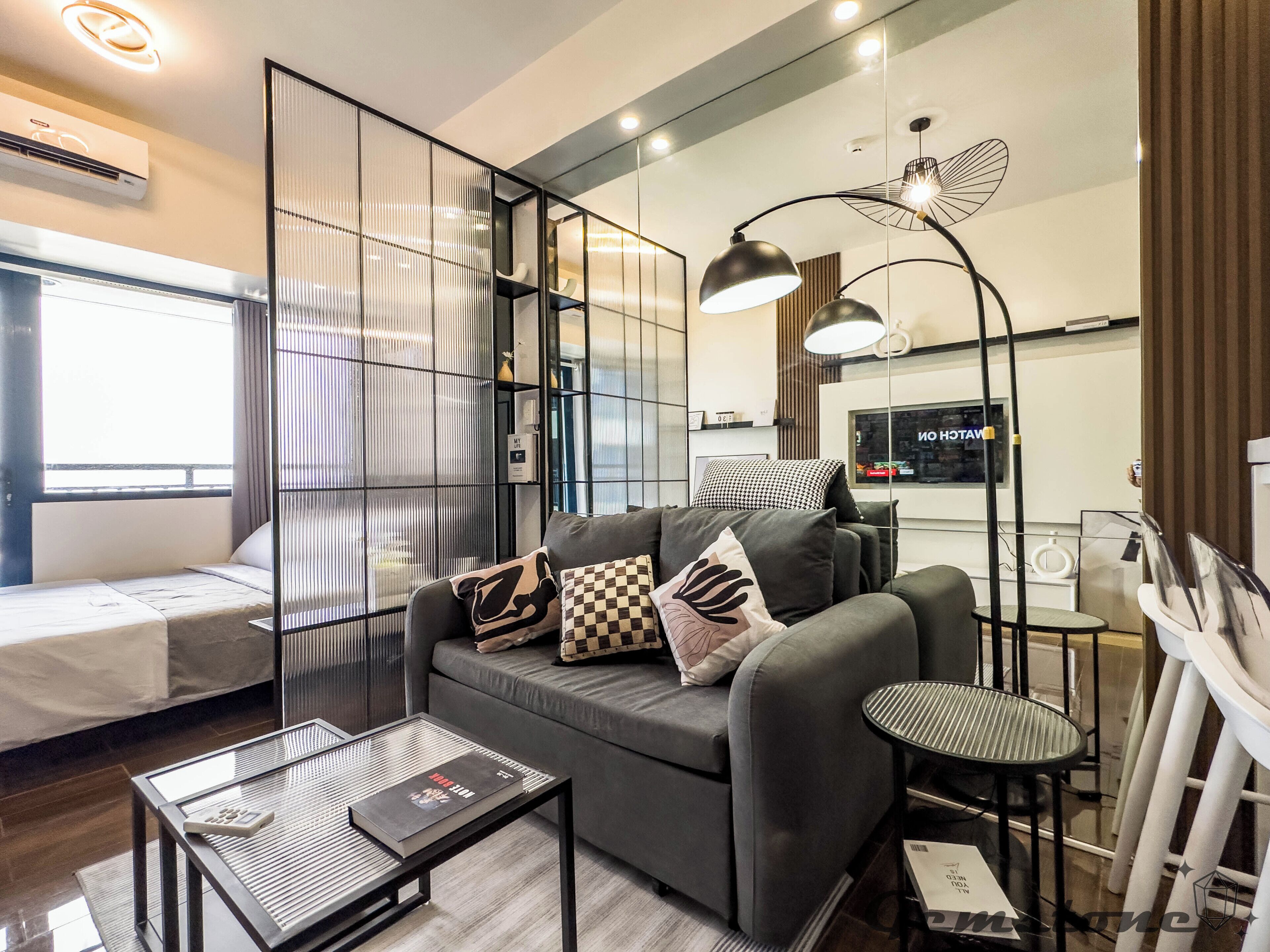 Un salon moderne avec un canapé, une table basse en verre et un lampadaire.