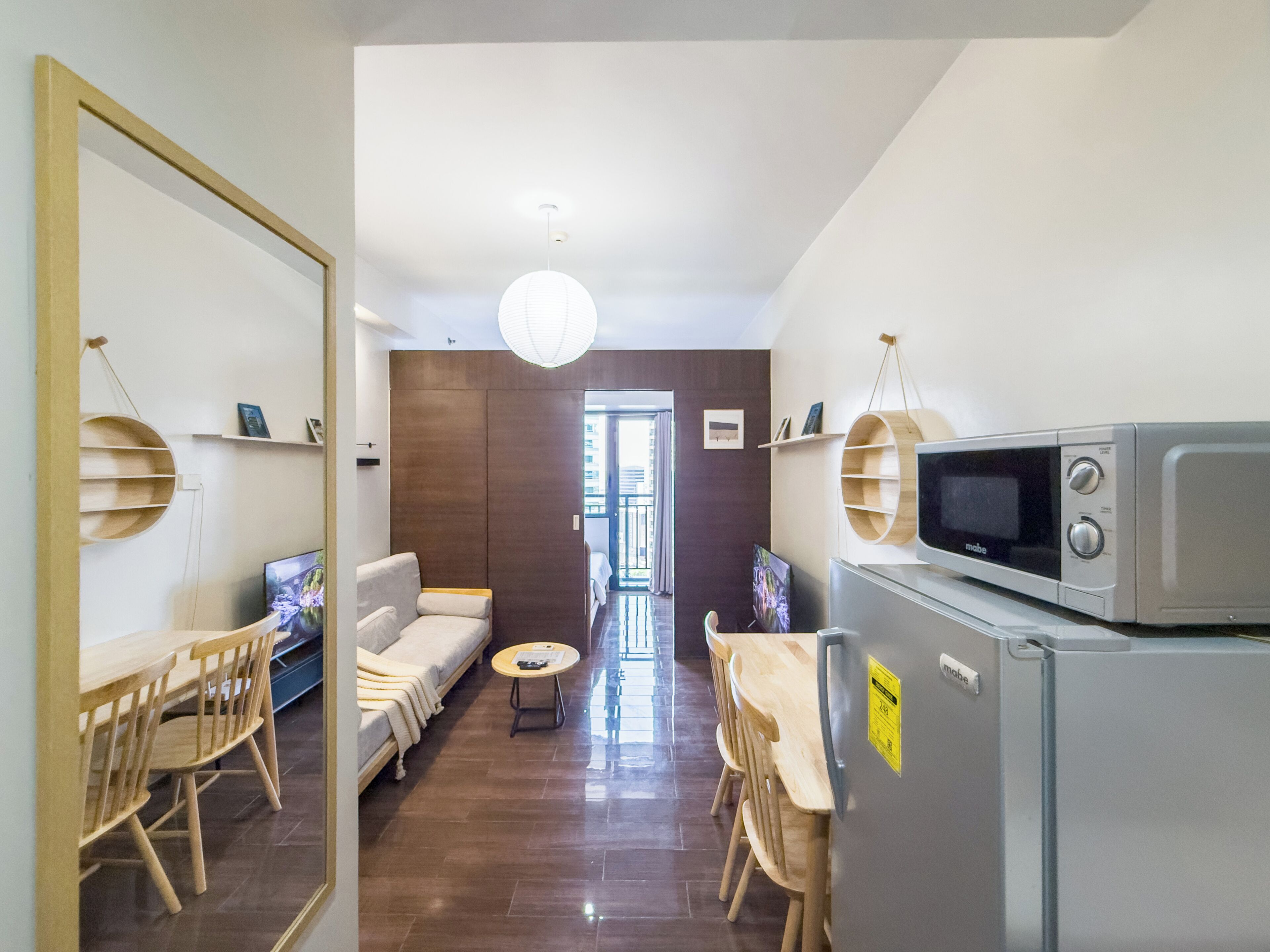 A modern living room with a sofa, chairs, a dining table, a TV, and a microwave.