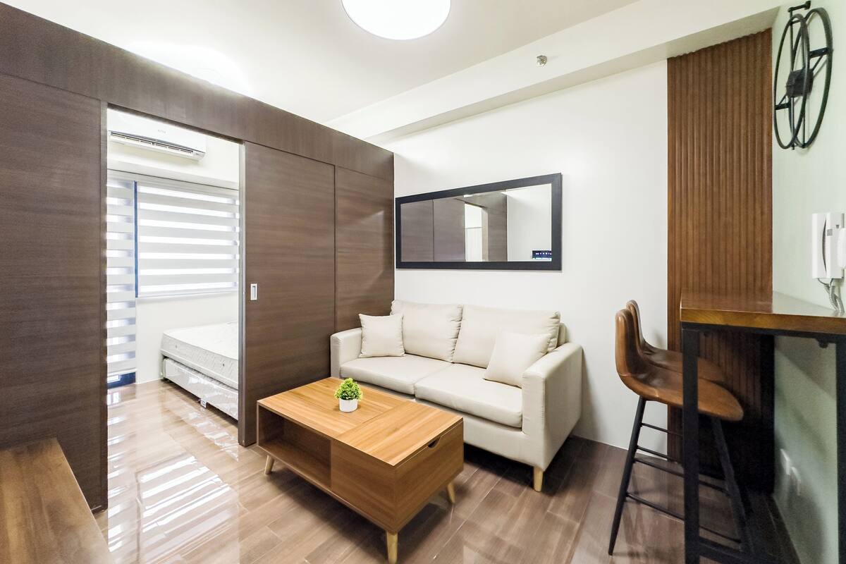 Una sala moderna con sofá, una mesa de centro de madera, un espejo y una bicicleta colgada en la pared.