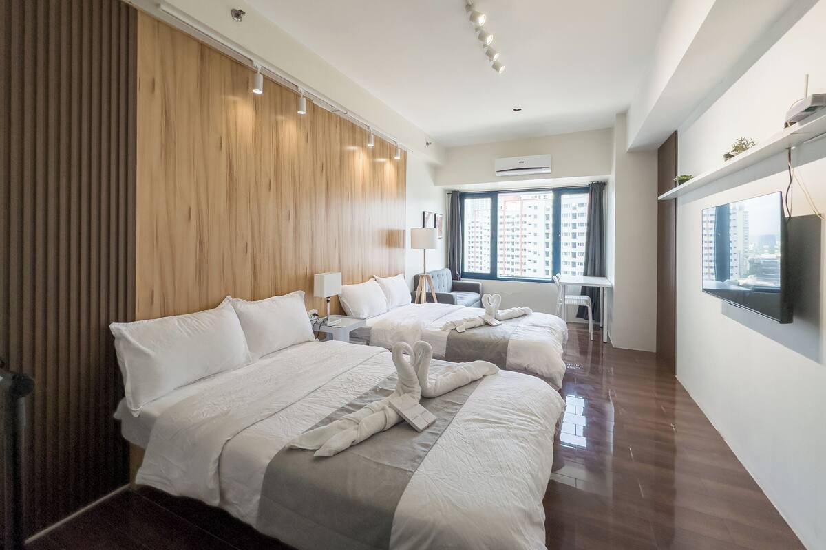 Una habitación de hotel moderna con una cama grande, un escritorio y un televisor.
