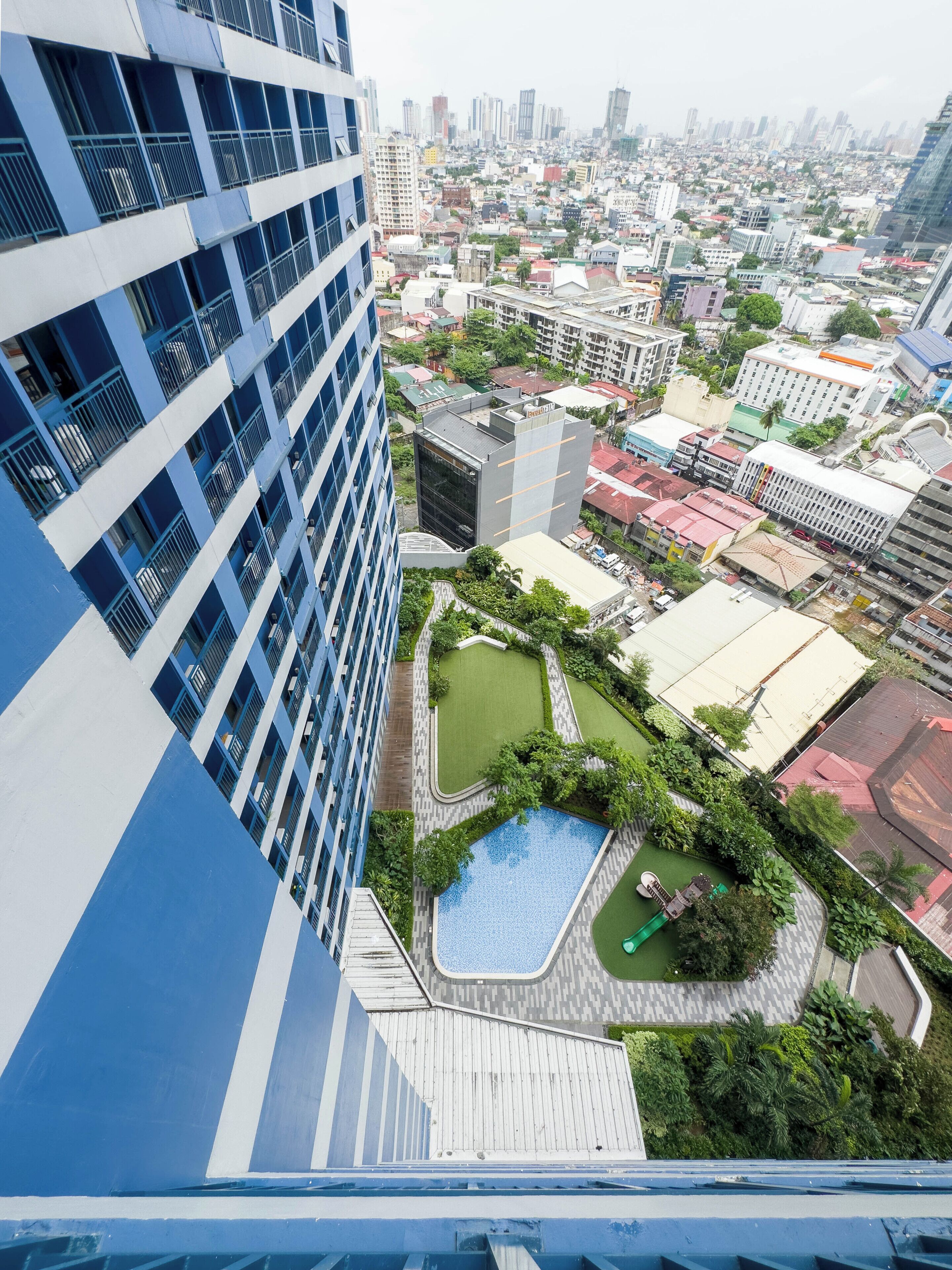 A high-rise building with a rooftop pool and surrounding greenery.