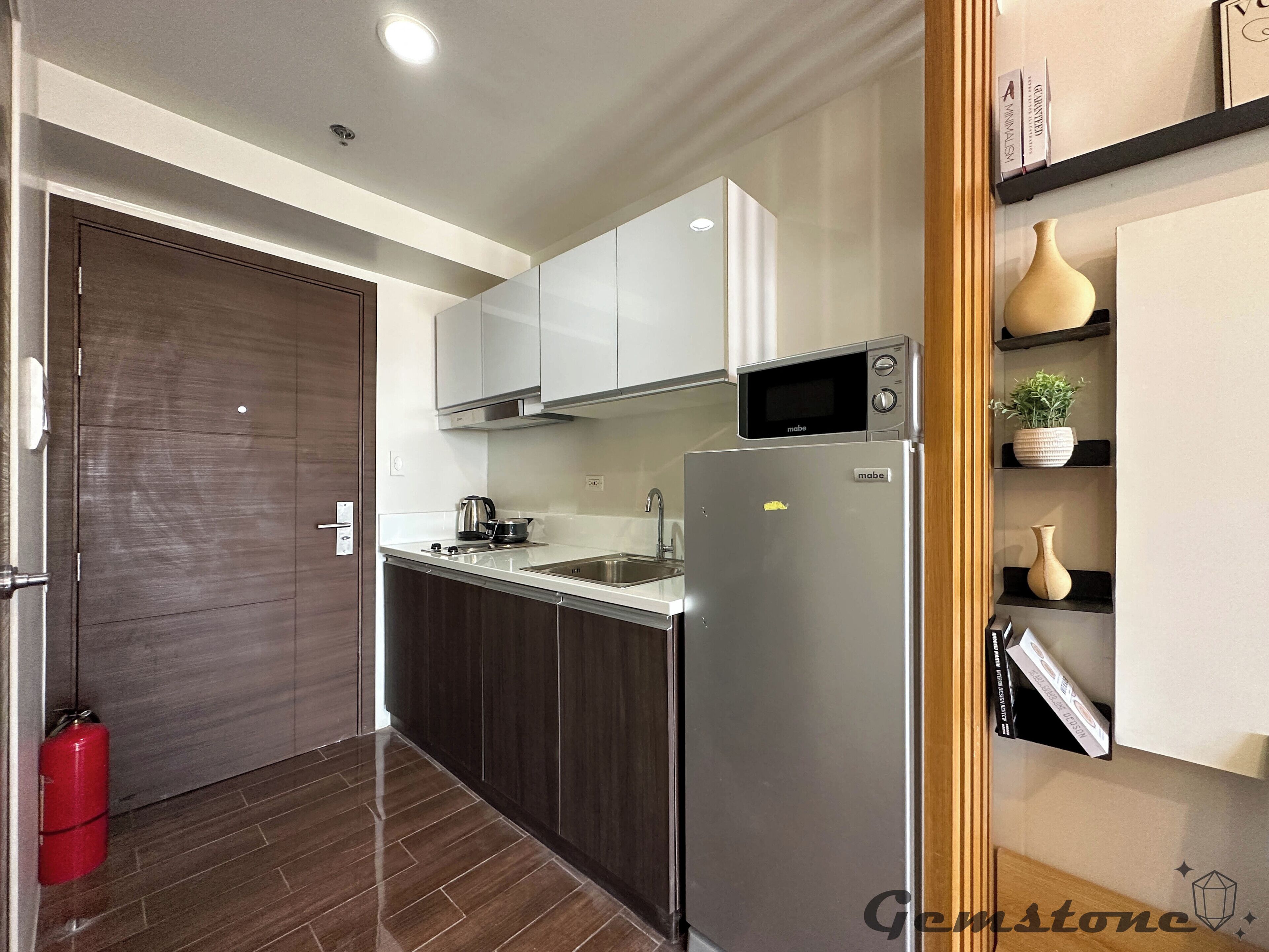 A modern kitchen with white cabinets, a stainless steel refrigerator, a microwave, and a sink.