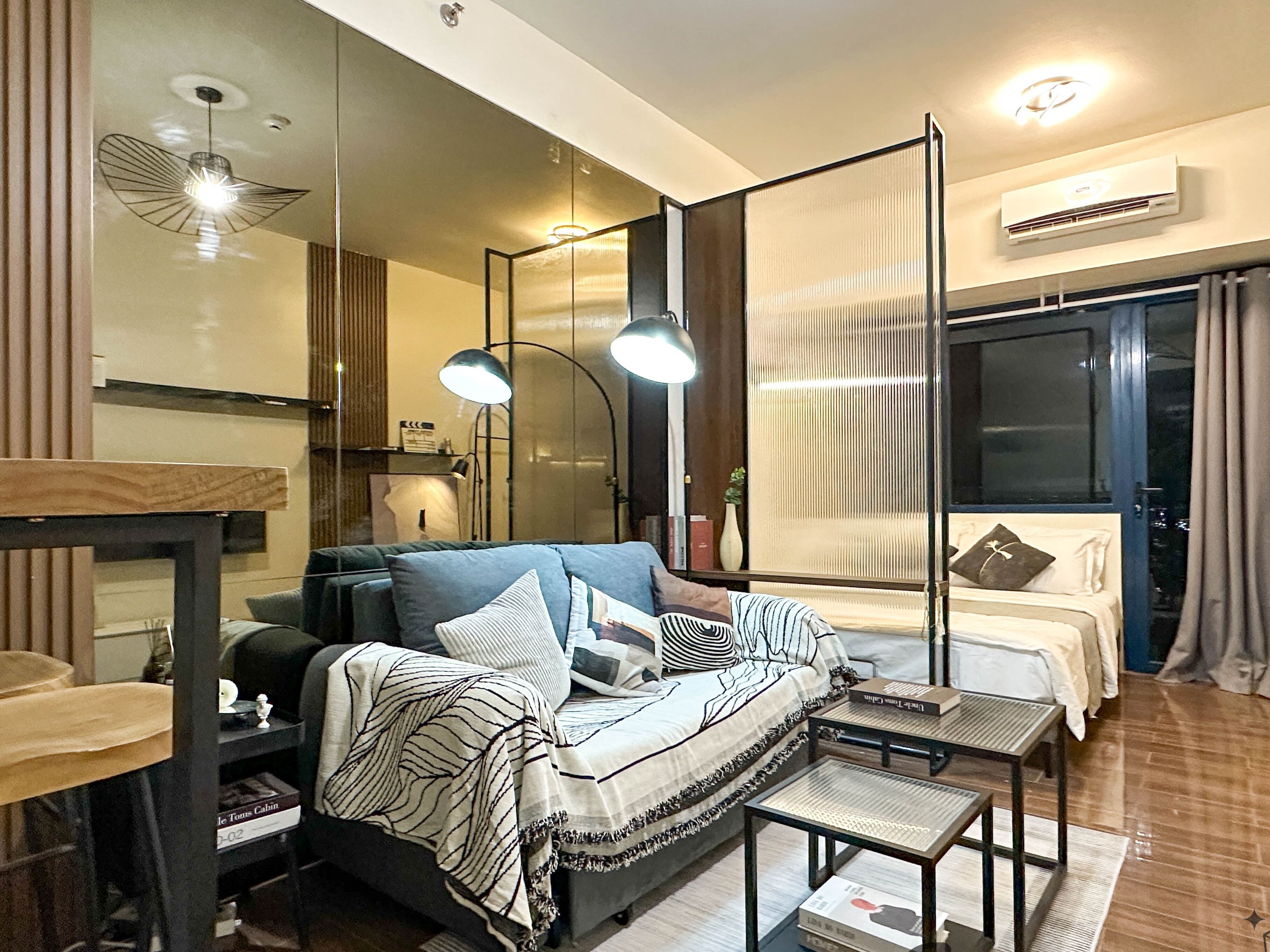 Une chambre moderne avec un canapé, une petite table, un miroir et une fenêtre.
