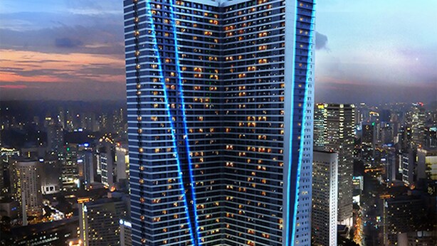 Een hoog hotel met modern design, met een opvallende verticale lichtbalk en een gebogen basis met aangelegde groenstroken.