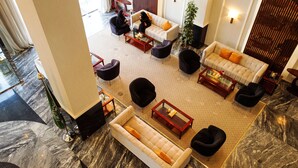 A spacious lobby with a marble floor, multiple seating areas including sofas and armchairs, and a large potted plant. - City Residence (Dammam)