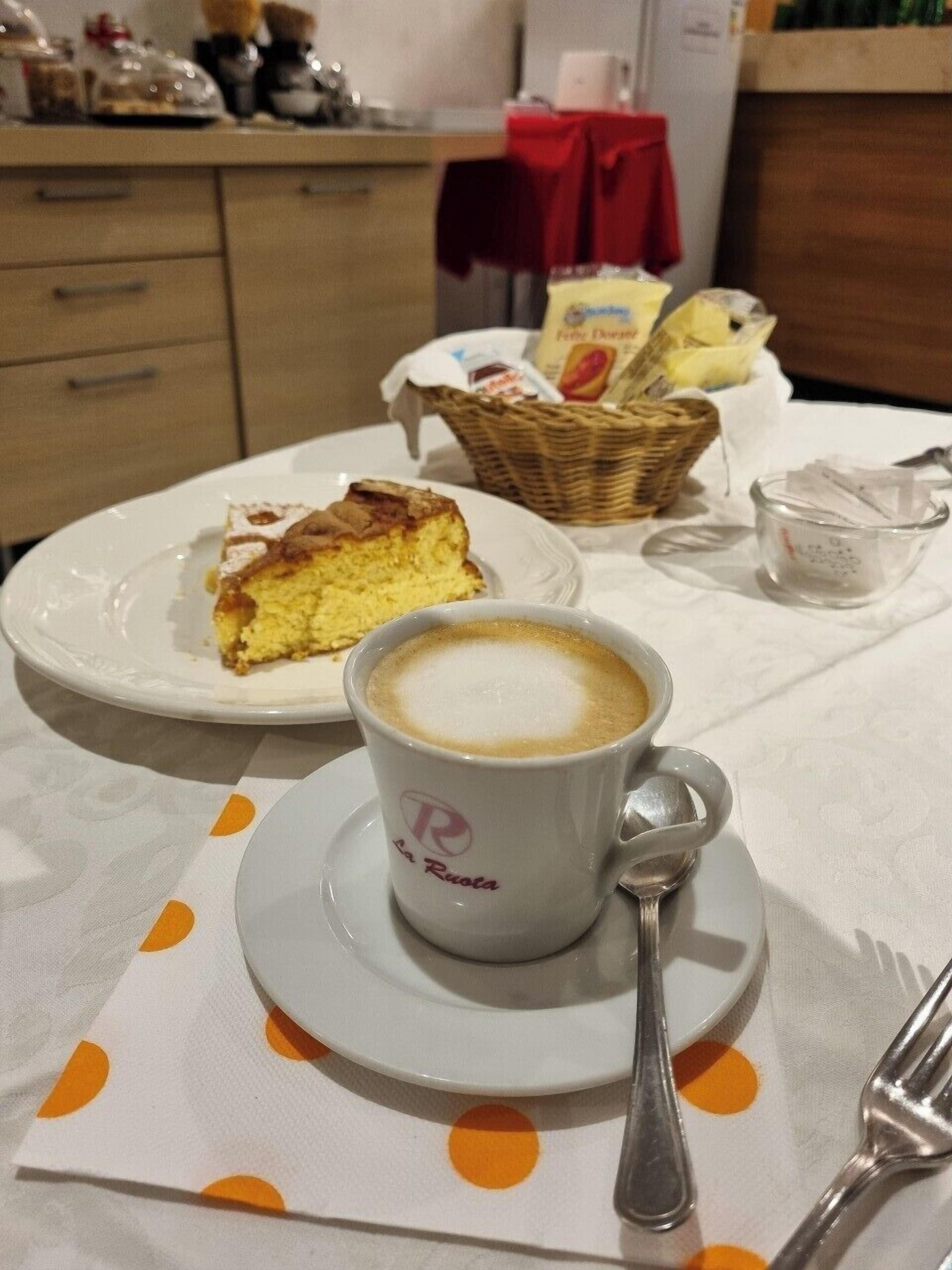 A table with a cup of coffee, a slice of cake, and a basket of bread.