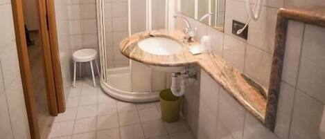 A modern bathroom with a sink, mirror, and shower.