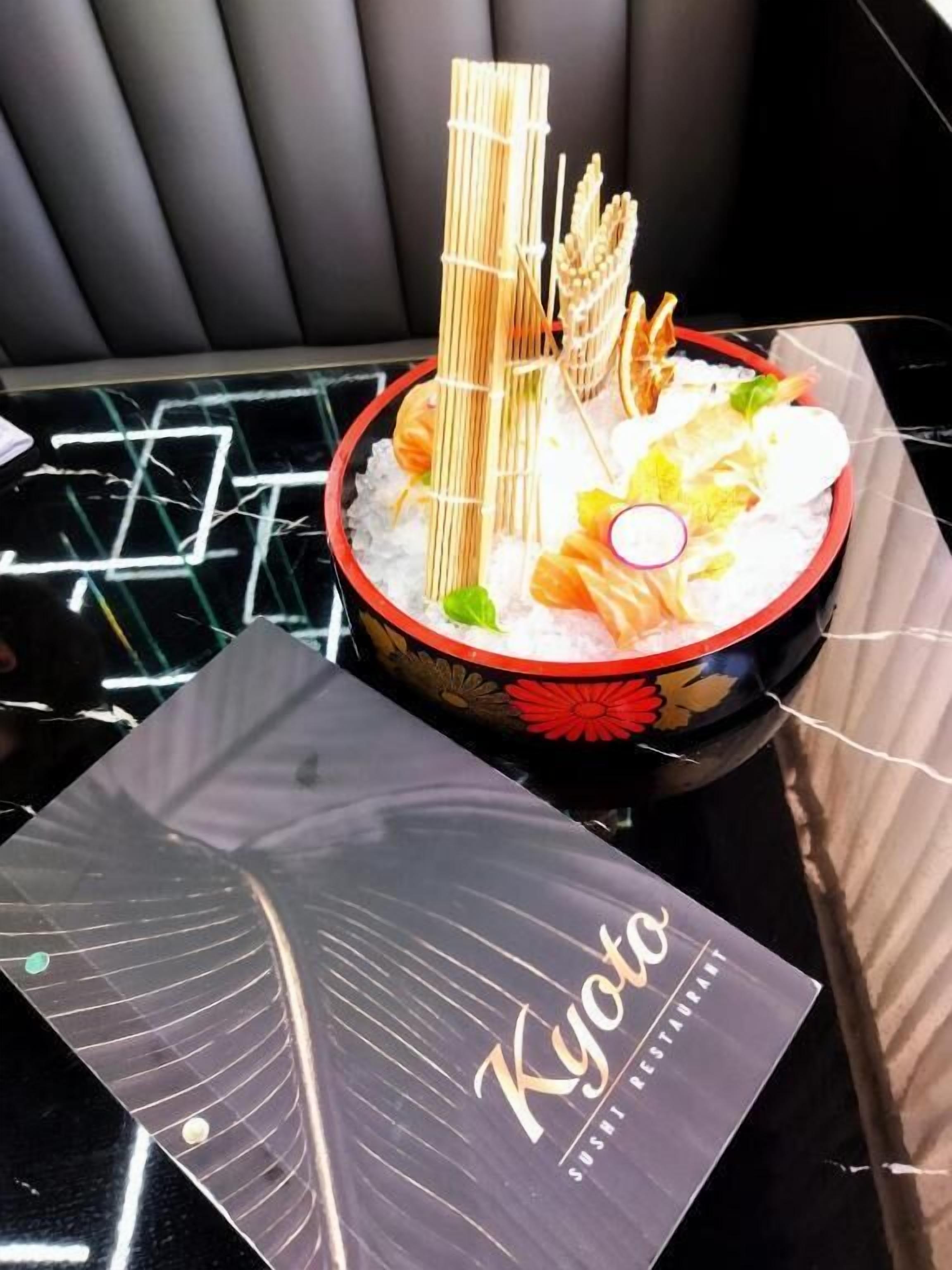 A sushi dish on a black table with a 'Kyoto Sushi Restaurant' placard.
