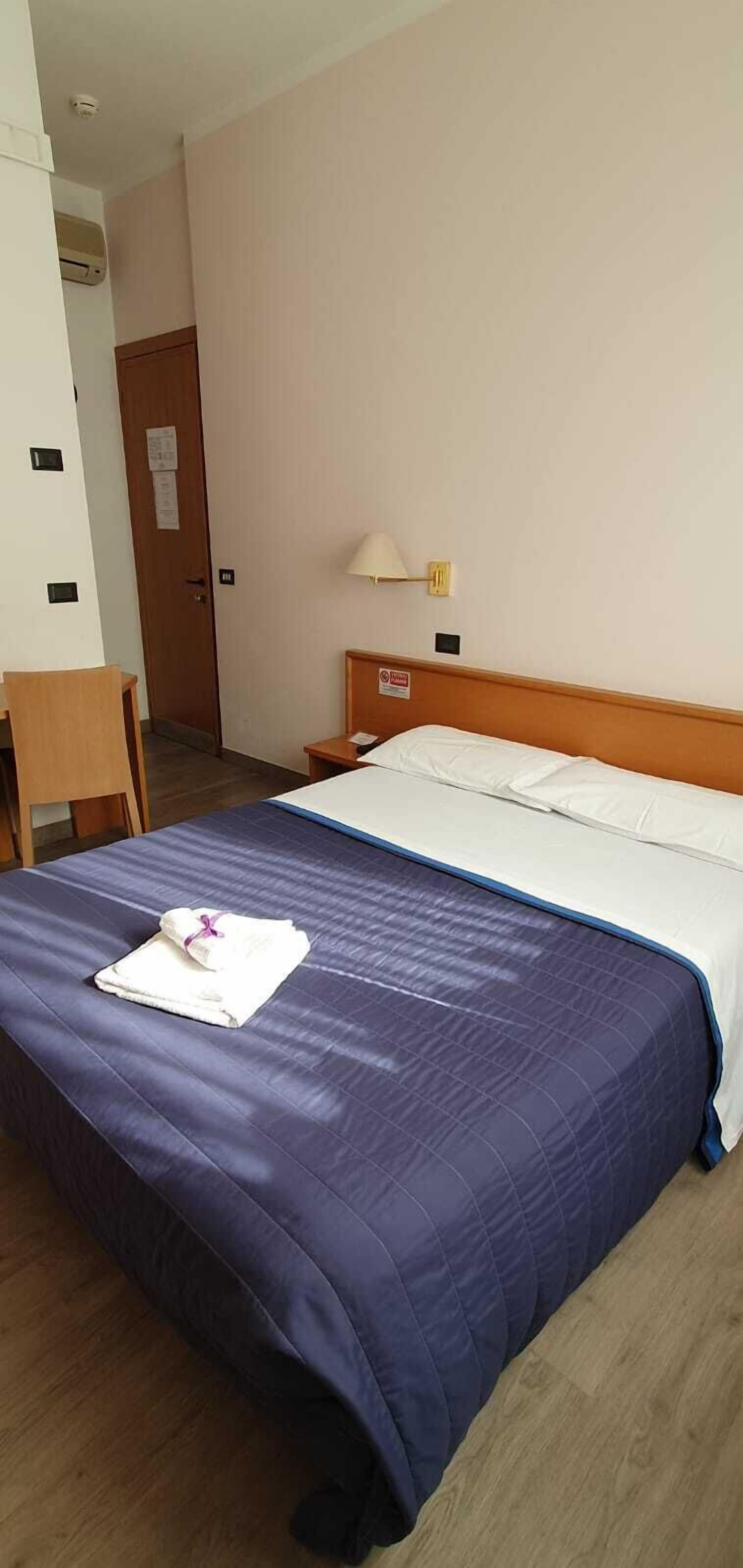 A hotel room with a bed, a desk, and a nightstand.