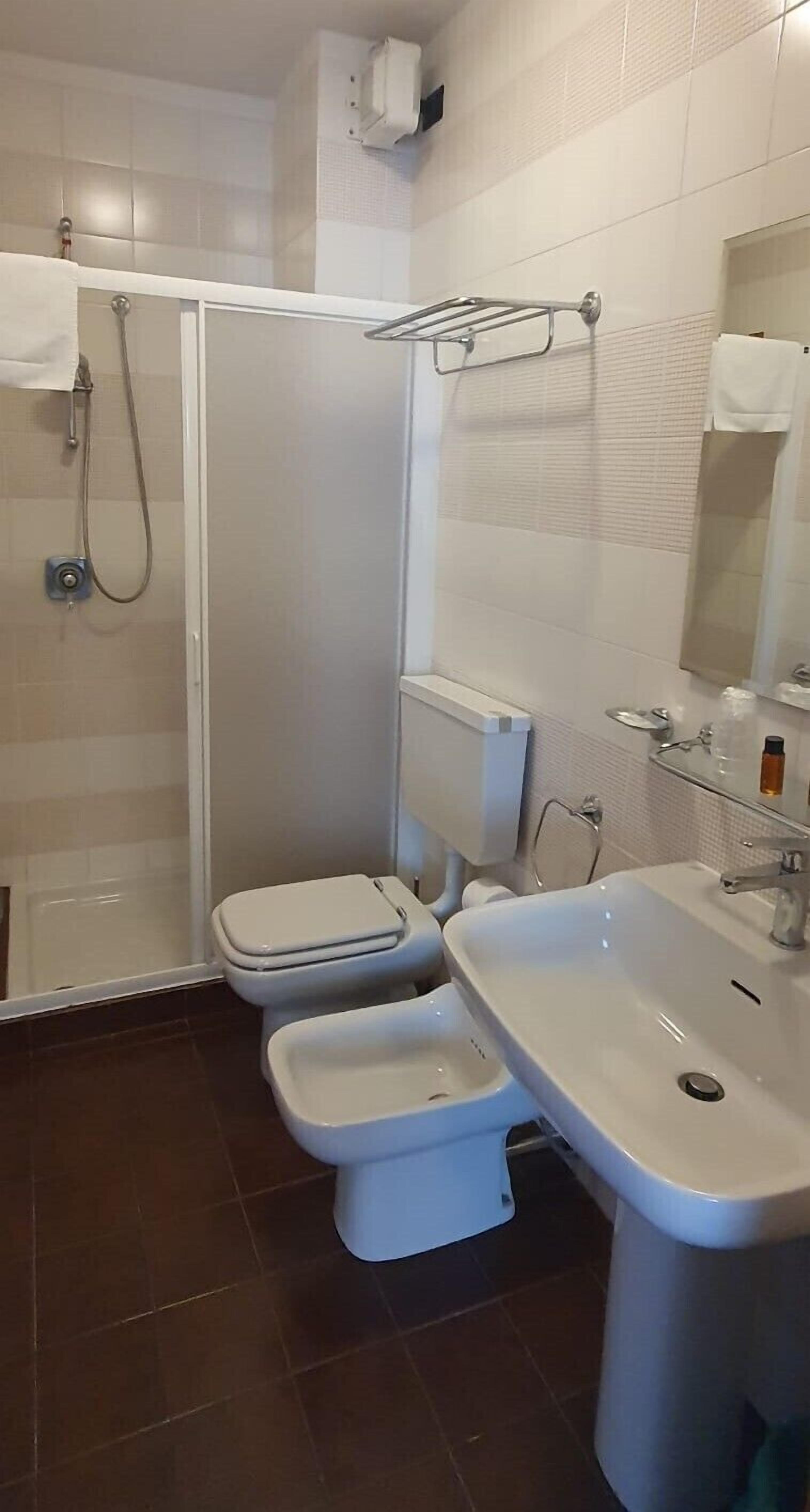 Une salle de bain équipée d’une douche, de toilettes, d’un bidet et d’un lavabo.