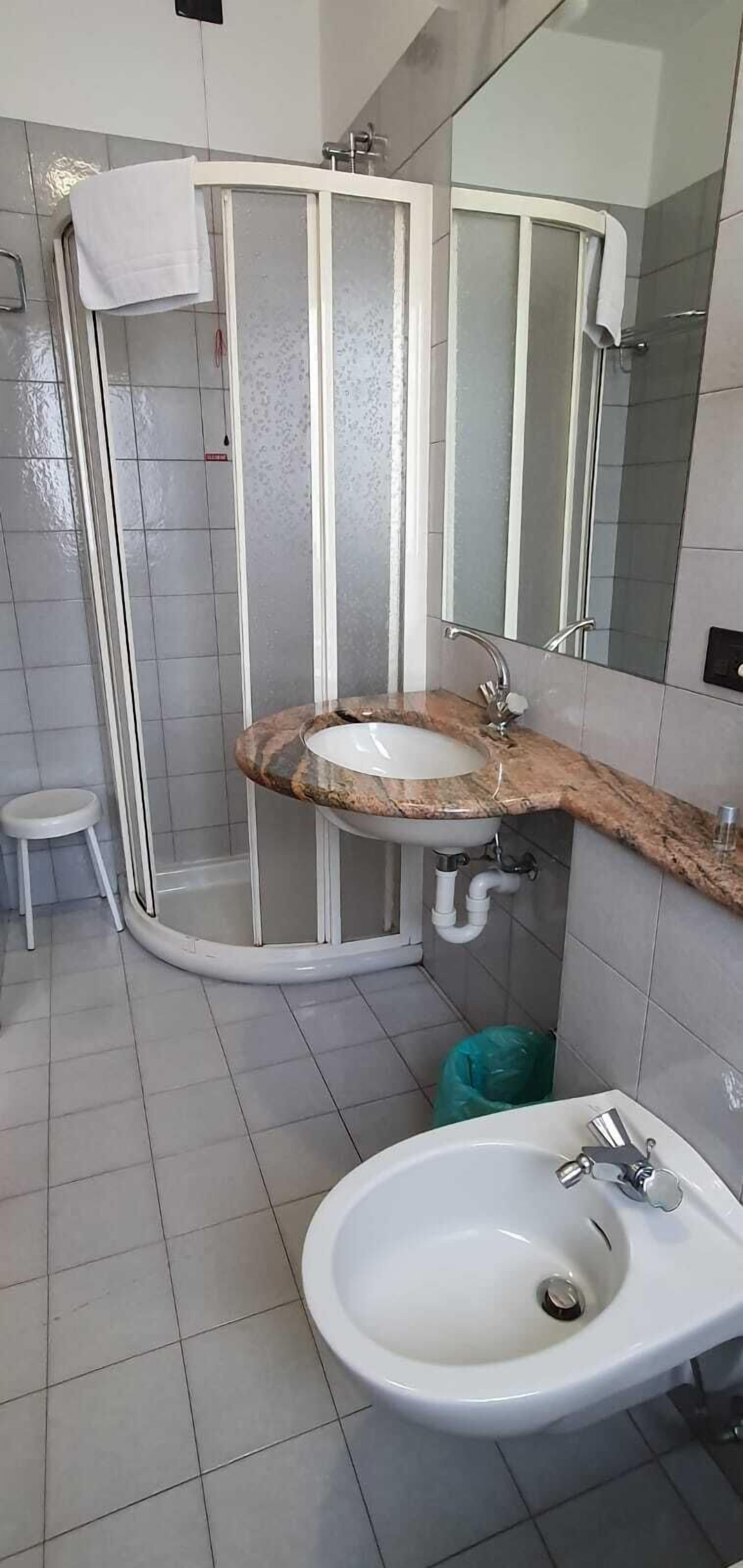 Een badkamer met douchecabine, wastafel en spiegel.