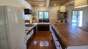Cocina con vigas de madera, estufa, lavabo, armarios y un ventanal grande.