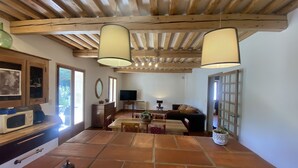 Amplia sala de estar con techo de madera, televisor grande y una mesa de comedor con sillas.