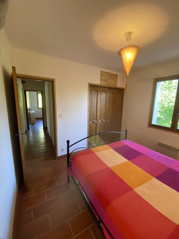A bedroom with a bed, a window, a door, and a hallway.