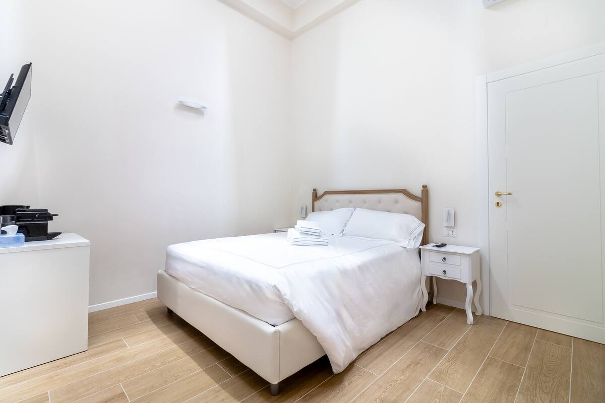 A neatly arranged bedroom with a bed, bedside tables, and a wardrobe.