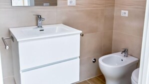 A bathroom with a white sink, a bidet, and a mirror above the sink. - Charme & Chic Nazionale (Rome)