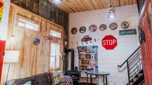 Un interior rústico con paredes de madera, chimenea visible, un letrero de Chevrolet y una señal de stop.