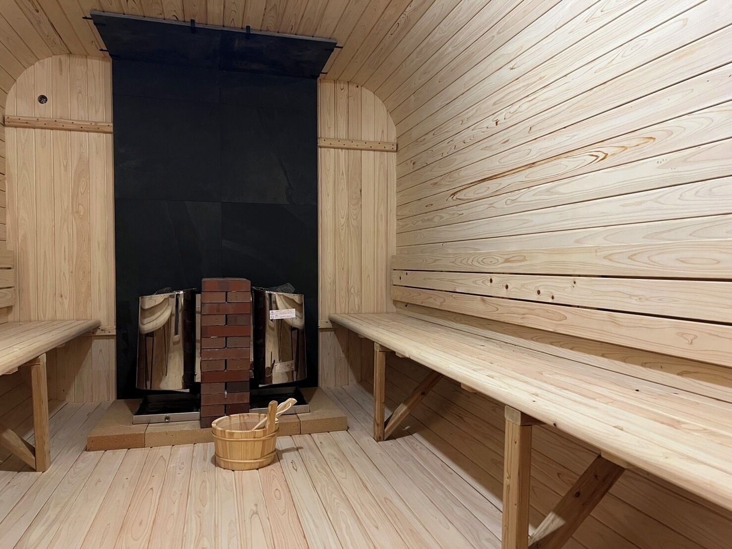 Una sauna con bancos de madera y pared de ladrillo.