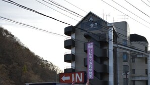 Un hôtel avec une enseigne indiquant la direction de l’entrée et un espace de stationnement où se trouve un fourgon blanc.