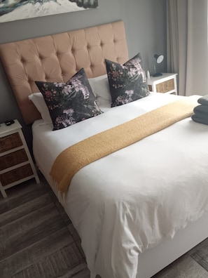 A neatly made bed with a tufted headboard, white bedding, and a brown throw blanket. - Charming 3-bedroom bed & breakfast in tranquil East London (East London)