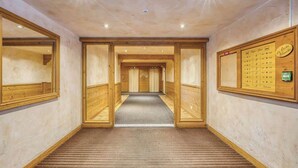 Un couloir d’hôtel avec des lambris en bois, un sol recouvert de moquette et un panneau d’information sur le mur de droite.