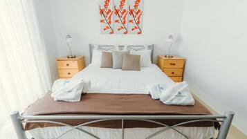 A neatly made bed with a brown blanket, two bedside tables with lamps, and a wall art piece above the bed.