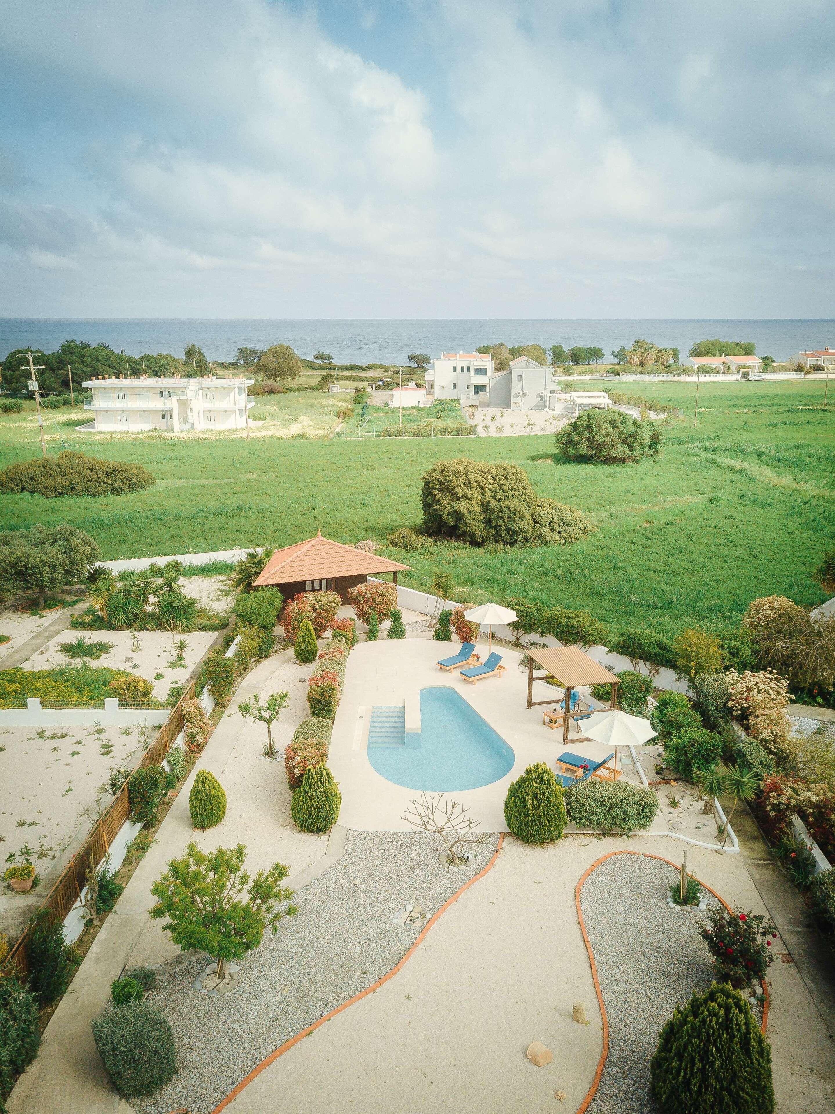 A residential area with a swimming pool, lounge chairs, and a view of the sea.
