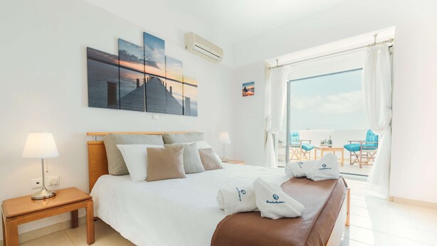 Een hotelkamer met een bed, een nachtkastje, een raam met uitzicht en kunst aan de muur.