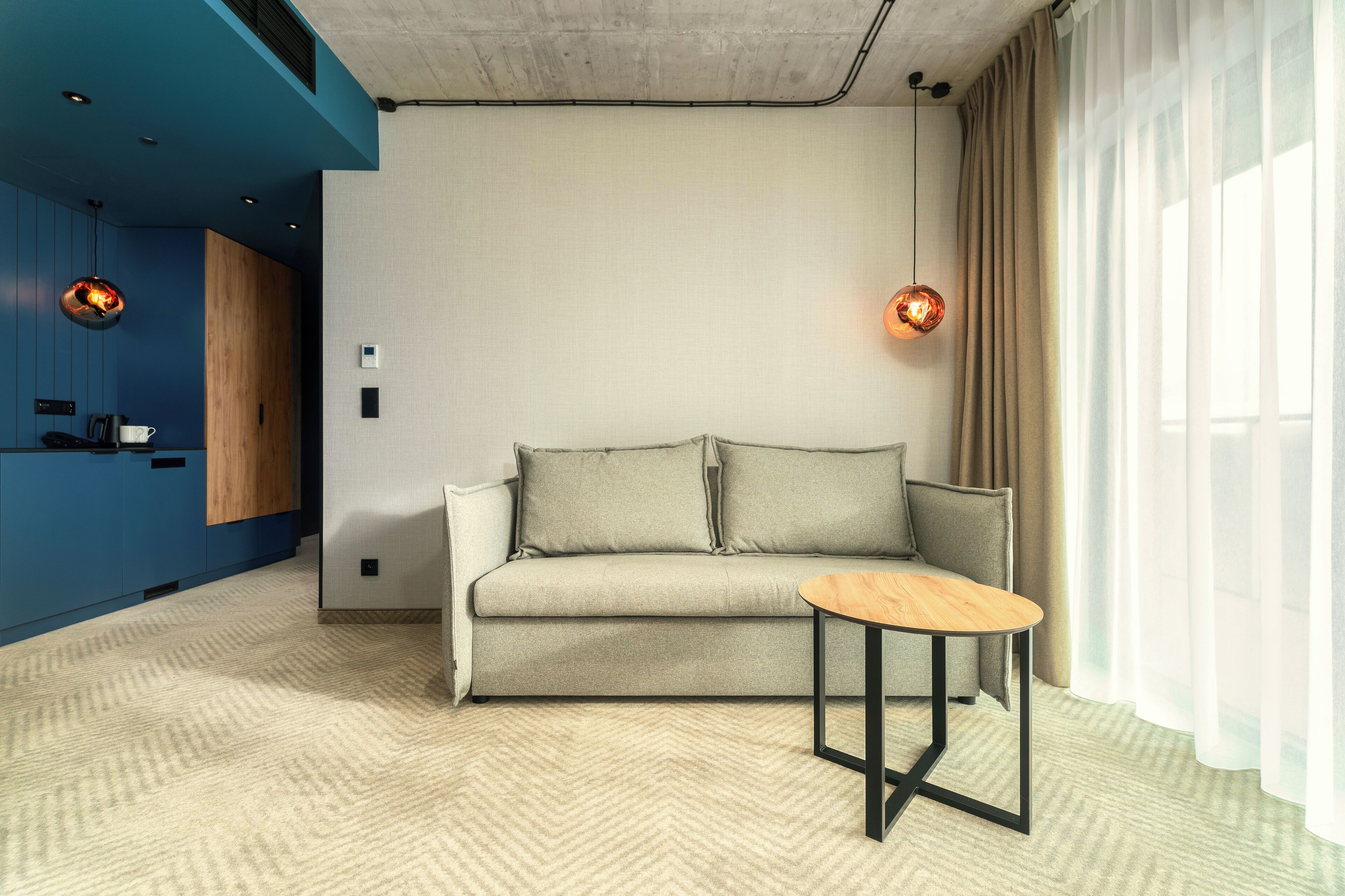Een moderne woonkamer met een bank, een klein rond tafeltje en hanglampen.