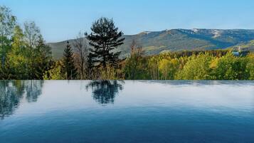 Una piscina exterior tranquil·la amb una vista clara d'una serralada boscosa al fons.