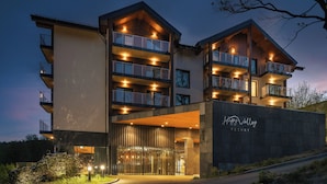 A modern multi-story hotel with balconies, a covered entrance, and a sign reading "Happy Valley Resort".
