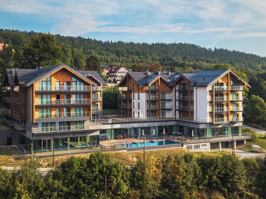 A modern hotel with multiple floors, balconies, and a swimming pool.