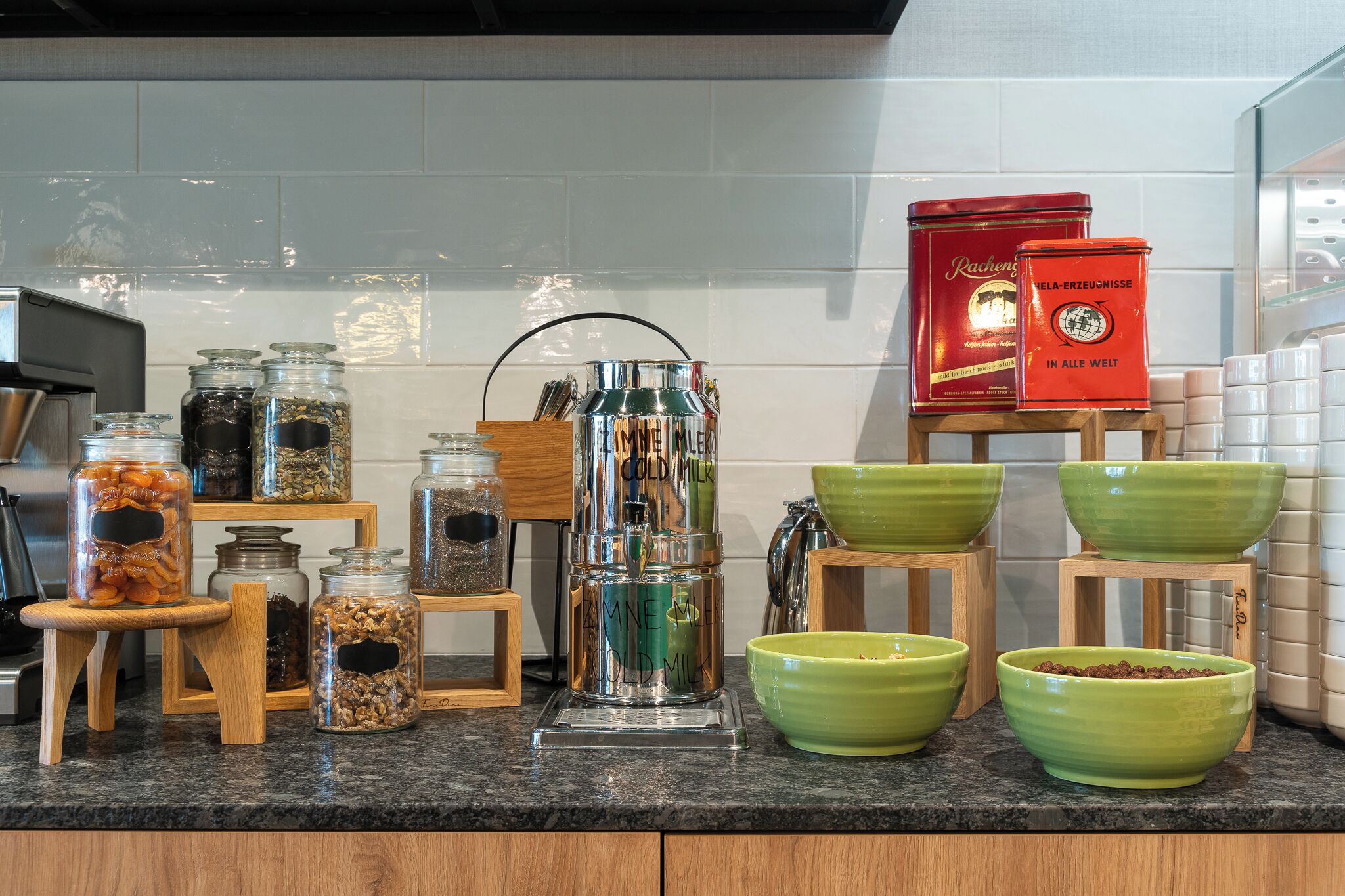A kitchen counter with various food items and containers, including jars of nuts and a large dispenser.